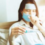 Asian women looking body temperature at oral thermometer for diagnosing flu from Coronavirus (Covid-19) infection self care stay at home.